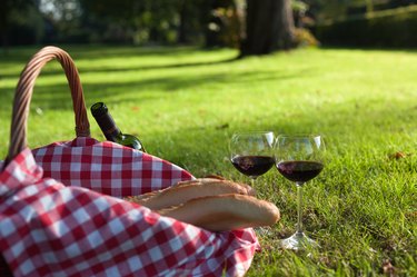 Picnic Basket with baguettes and glasses of wine on grass