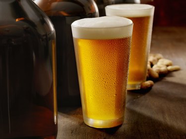 Beer growlers shown on a wooden counter with two glasses of beer