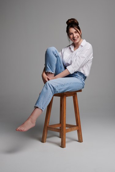 Studio shot of a beautiful young woman sitting on a chair against a grey background