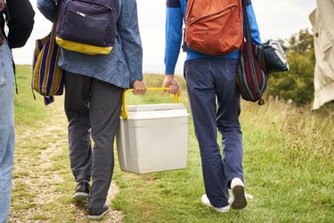 Two boys holding a cool box walking to a camping spot