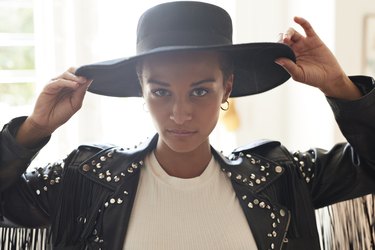 Portrait of confident young woman holding black hat