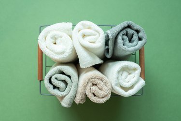 Rolled towels in basket against green background