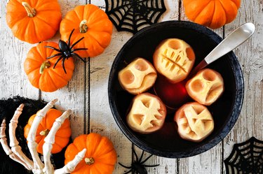 Spooky Halloween apple head punch table scene on white wood