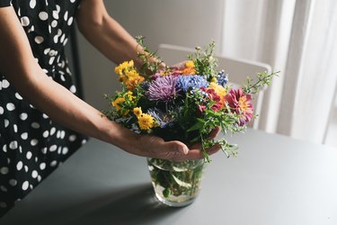 woman arranging a bouquet of flowers in a glass vase