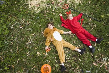 Boys in lion and devil costumes lying down in grass