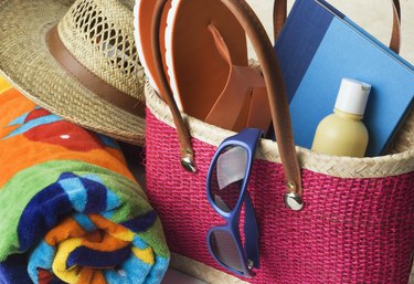 Hot Pink Woven Beach Bag with Suntan Lotion, Towel, Sunglasses, Hat, and Book.