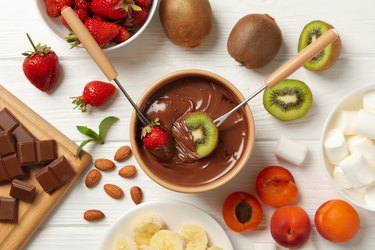 Chocolate fondue on white wooden background