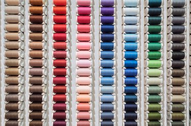 Front view of a many spools of thread of different colors displayed in a store for sale.