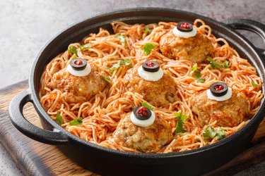 halloween Spaghetti with tomato sauce and meatballs with eyes in a pan on the table close-up. Horizontal