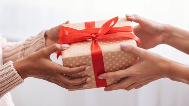 Female hands holding and giving present to woman