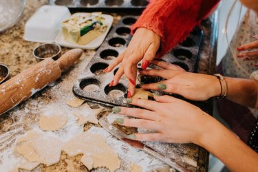 Close-up of two young woman in a kitchen, baking mince pies