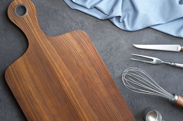 Wood cutting board and kitchen utensils on a concrete background