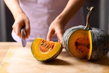 Asian pumpkin on cutting wooden board prepared for cooking
