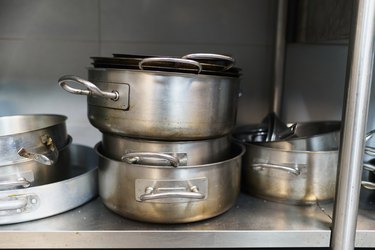 Close-up of stainless steel pans and pots stacked in a commercial kitchen