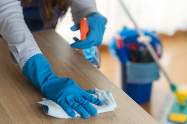 Housemaid cleans the table.Mop and blue bucket with the detergents in the background