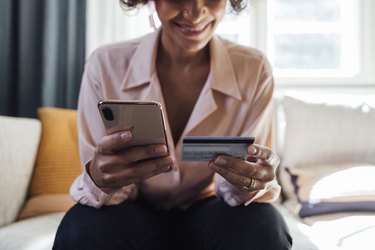 A Close Up Shot Of An Unrecognizable Mixed-race Woman Using He Credit Card And Typing On Her Smartphone