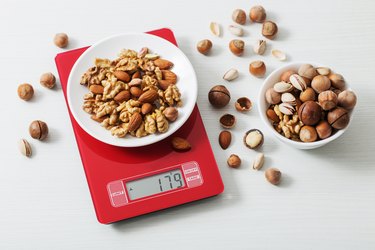 mix of different nuts on  kitchen scale on a white table