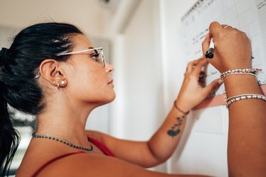 woman writing on the calendar in the kitchen