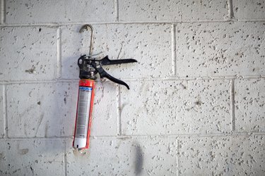 Caulking Gun hanging on the white stone wall