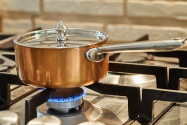 Copper saucepan over low heat on stove to make sauce