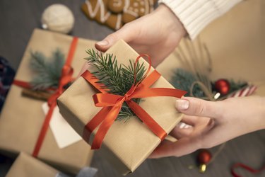 Gift box with Christmas decoration in female hands. Close-up. Concept of winter holidays.
