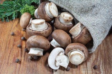 Royal mushrooms mushrooms, whole and cut into pieces poured out of the bag, scattered pepper, parsley,dill, close-up on a wooden background, rustic style