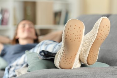 Woman with slippers resting on a couch at home