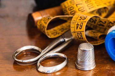 Close-up of thread, tape measure, scissors, thimble and dressmaker's objects.