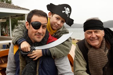 Grandfather, father and grandson (10-11) wearing pirate costumes outdoors, portrait