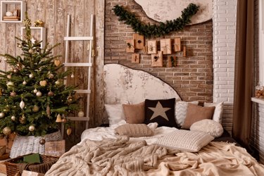 Modern cozy interior in white and brown shades with the bed and decorated Christmas tree. Christmas gifts, garlands and other decorations