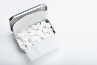 Mint candies on a white background. White mint candies in an open tin box. Fresh breath or bad breath concept