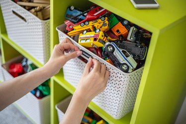 Woman hands applying sticker with name title of children toys for comfortable sorting and storage