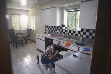 Woman repairing kitchen sink at home