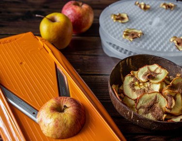 Apples being sliced by mandoline to be dried