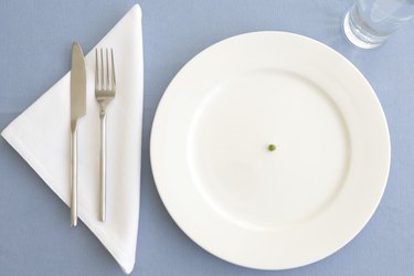 Place setting with green pea in center of plate, overhead view