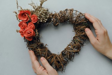 Female hans holding heart shaped floral wreath