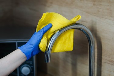 Hand in gloves cleaning the sink