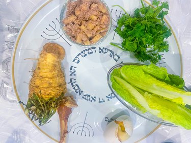 Seder plate with horseradish, shankbone, roasted egg, lettuce, parsley and charoset.
