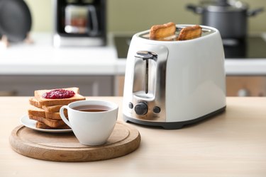 Toaster with bread slices and cup of coffee on table