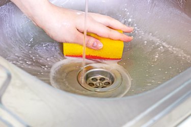 Cleaning metal sink with sponge.