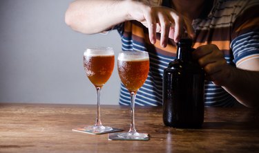 Unrecognizable man serving homebrew in glasses with growler. Fresh craft beer tasting.