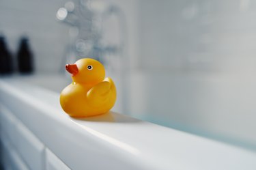 Yellow toy rubber duck on side of bath