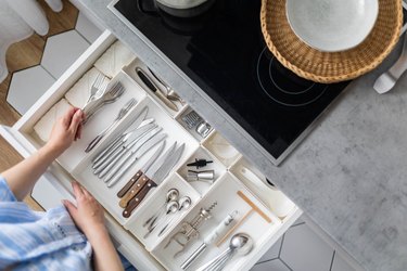 Top view closeup housewife hands tidying up cutlery in drawer general cleaning at kitchen