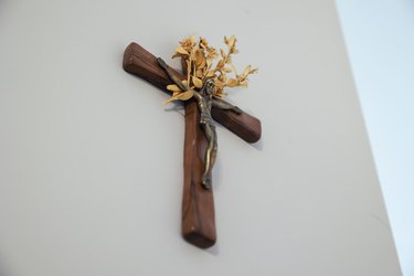 Low angle of a wood crucifix with yellow flowers hanging from a white wall - a religious concept