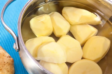 Peeled potatoes in pot with water
