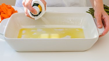 Woman using olive oil spray on a white ceramic baking dish,California,United States,USA