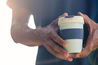 Man holding a reusable travel coffee mug