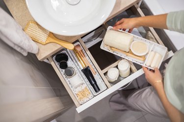 Neatly organizing bathroom amenities and toiletries in drawer in bathroom