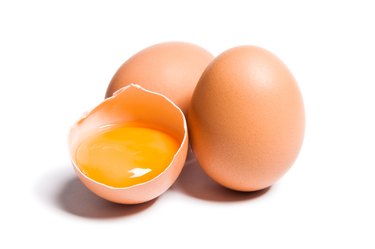 Group of brown raw eggs, one broken and showing yolk