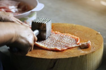 Close-Up Of Hand Holding Bread On Cutting Board